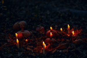 candles burning next to pumpkins outside