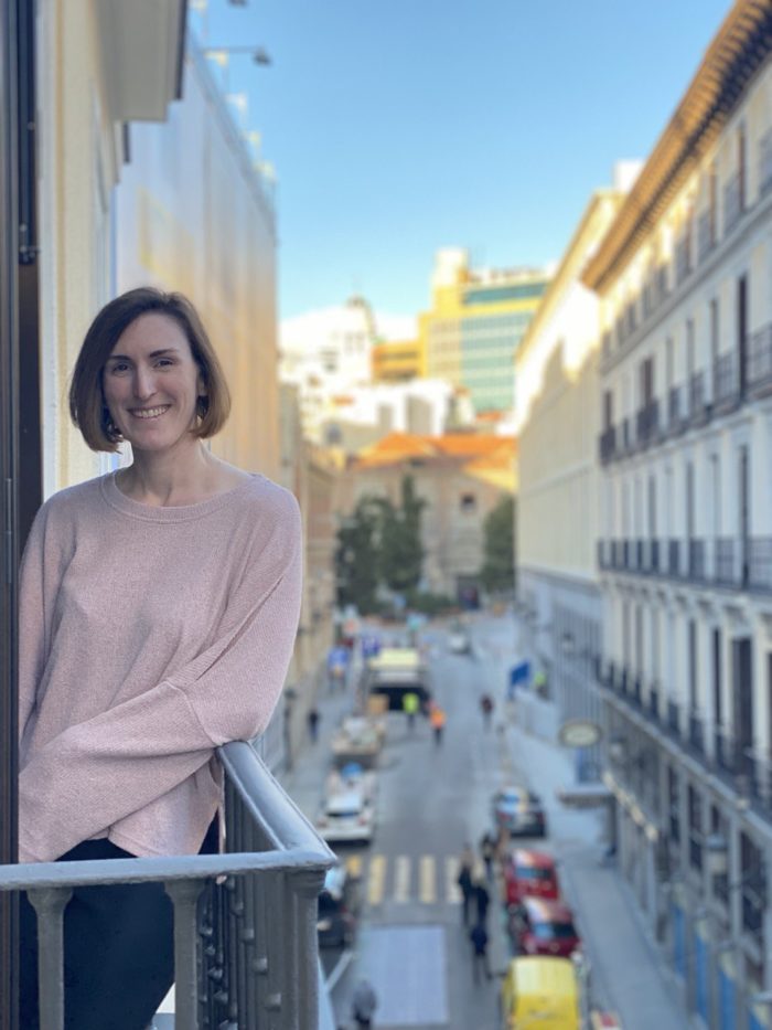 woman leaning against a balcony with a city street in the background
