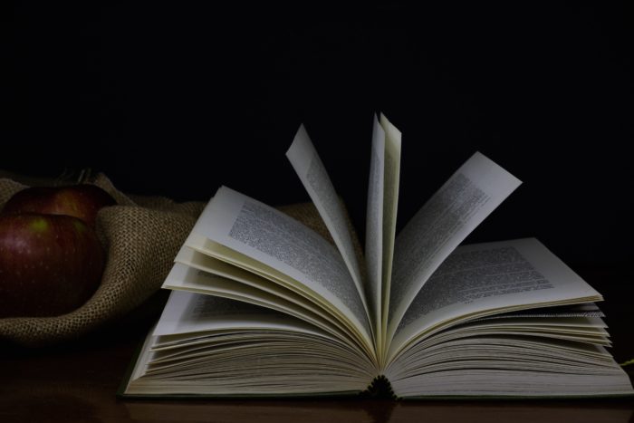 open book with an apple next to it