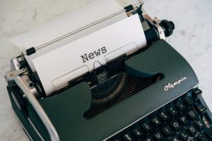 typewriter with paper inside it that reads news