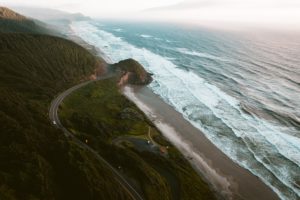 oregon coastline with highway weaving through the trees to the left and the beach to the right